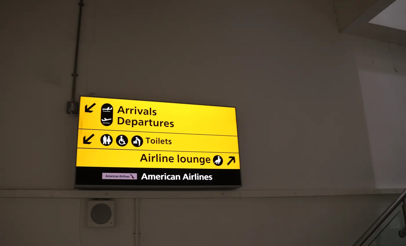 Yellow airport signs pointing to arrivals, departures and airline lounges at Heathrow